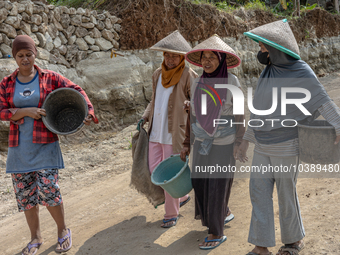 Women walks in a broken road as they help villagers to renovate a broken village road at Kebumen, Central Java, Indonesia on August 20, 2023...