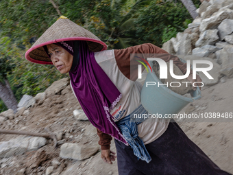 A woman carries a bucket of sand and stone as she helps villagers to renovate a broken village road at Kebumen, Central Java, Indonesia on A...