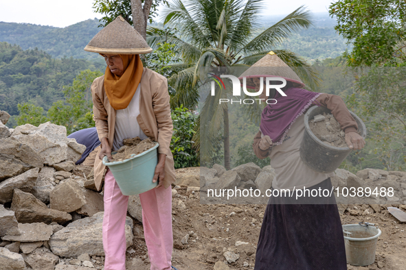 A woman carries a bucket of sand and stone as she helps villagers to renovate a broken village road at Kebumen, Central Java, Indonesia on A...