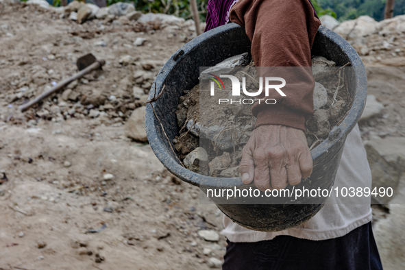 A woman carries a bucket of sand and stone as she helps villagers to renovate a broken village road at Kebumen, Central Java, Indonesia on A...