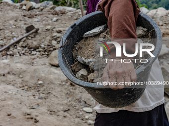 A woman carries a bucket of sand and stone as she helps villagers to renovate a broken village road at Kebumen, Central Java, Indonesia on A...