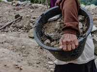 A woman carries a bucket of sand and stone as she helps villagers to renovate a broken village road at Kebumen, Central Java, Indonesia on A...