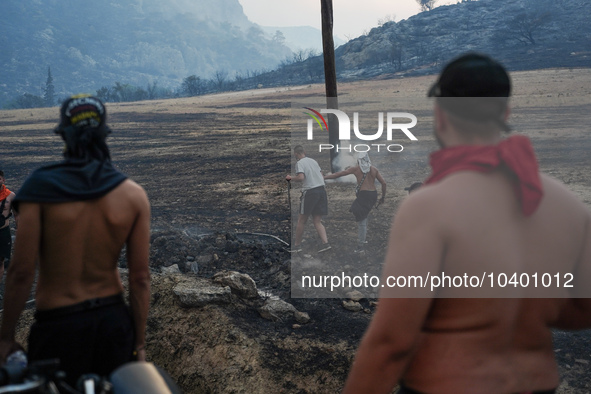 Residents try to put out a fire from a power pole during the Mount Parnitha fire on 23/8/23 