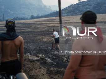 Residents try to put out a fire from a power pole during the Mount Parnitha fire on 23/8/23 (