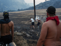 Residents try to put out a fire from a power pole during the Mount Parnitha fire on 23/8/23 (