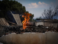 A flame is leaping from the wall of a fire-damaged house on Mount Parnitha in Athens, Greece, on  August 23, 2023 (