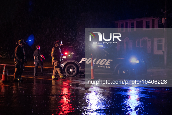 ROYAL OAK, MI - AUGUST 24, 2023: Royal Oak police officers and firemen from the Royal Oak Fire Department blockade a flooded street after a...