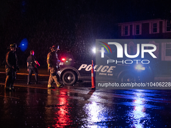 ROYAL OAK, MI - AUGUST 24, 2023: Royal Oak police officers and firemen from the Royal Oak Fire Department blockade a flooded street after a...