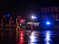 ROYAL OAK, MI - AUGUST 24, 2023: Royal Oak police officers and firemen from the Royal Oak Fire Department blockade a flooded street after a...