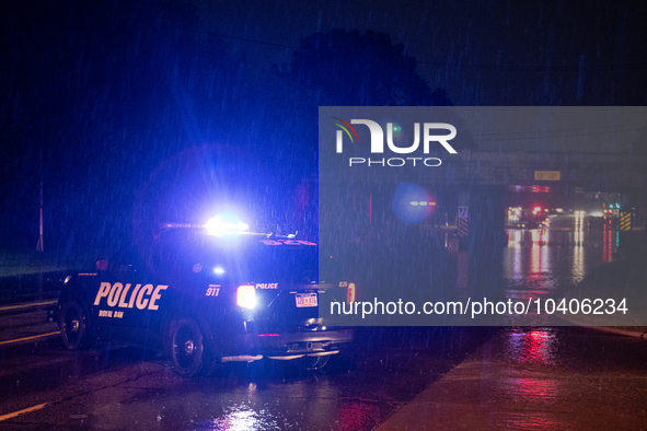 ROYAL OAK, MI - AUGUST 24, 2023: Royal Oak police officers and firemen from the Royal Oak Fire Department blockade a flooded street after a...