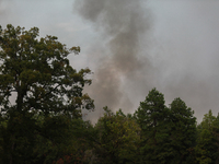 Heavy smoke from a large wildfire is seen rising from behind trees on September 2, 2023, near Huntsville in Walker County, Texas.  (