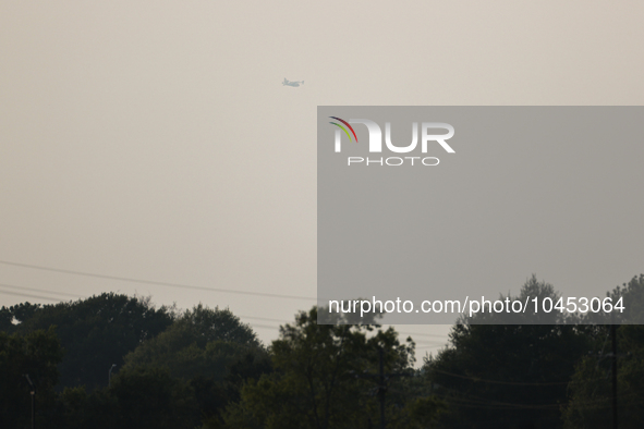 A firefighting aircraft is seen in the distance through the wildfire haze near Huntsville in Walker County, Texas.  