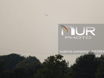 A firefighting aircraft is seen in the distance through the wildfire haze near Huntsville in Walker County, Texas.  (