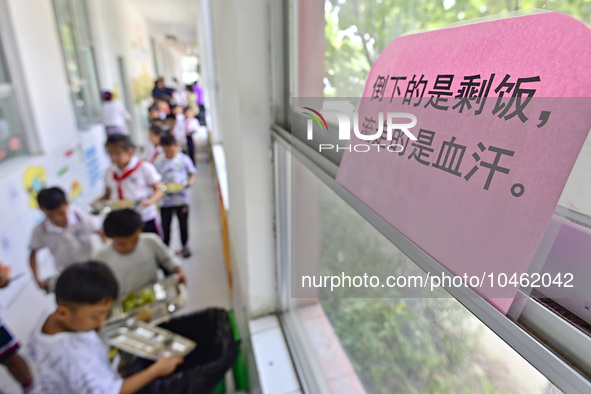 Students line up to dump leftovers from their meals into a trash can at Yanghe Primary School in Gaoliu town, Qingzhou city, East China's Sh...