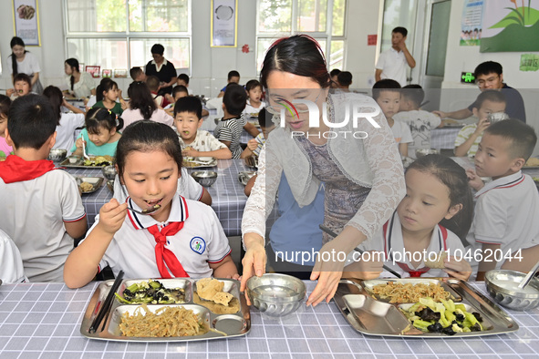 A teacher serves hot water to a student at Yanghe Primary School in Gaoliu town, Qingzhou city, East China's Shandong province, Sept 4, 2023...