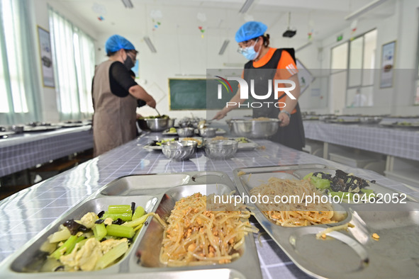 A restaurant staff distributes lunch for students at Yanghe Primary School in Gaoliu town of Qingzhou city, East China's Shandong province,...