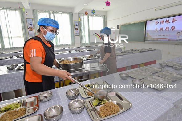 A restaurant staff distributes lunch for students at Yanghe Primary School in Gaoliu town of Qingzhou city, East China's Shandong province,...