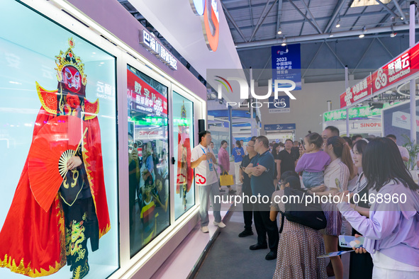  Visitors enjoy a face-changing interactive performance at the booth of CHINA Telecom at the 2023 SMART CHINA EXPO in Chongqing, China, Sept...