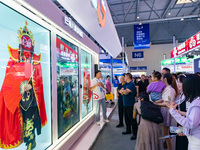  Visitors enjoy a face-changing interactive performance at the booth of CHINA Telecom at the 2023 SMART CHINA EXPO in Chongqing, China, Sept...