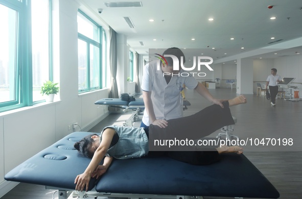 A medical worker massages a citizen's lower limbs at the rehabilitation center of Hangzhou Rehabilitation Hospital in Hangzhou, east China's...