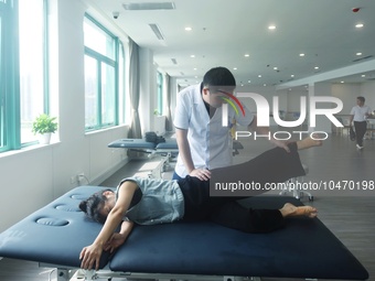 A medical worker massages a citizen's lower limbs at the rehabilitation center of Hangzhou Rehabilitation Hospital in Hangzhou, east China's...