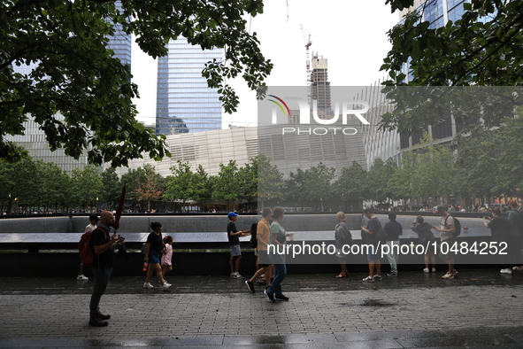 Visitors gather to pay tribute to the victims of 9/11 attacks near one of two reflecting pools at the National September 11 Memorial & Museu...