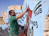 Graffiti artist Aziz Al-Asmar paints a painting on the wall of a destroyed house in the town of bench rural Idlib in solidarity with the vic...