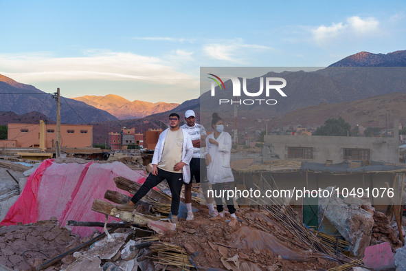 Three young people stand on a pile of rubble in the village of Ijoukak, which has been completely leveled by the earthquake. 