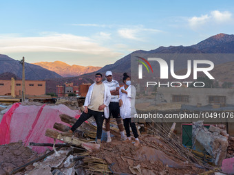 Three young people stand on a pile of rubble in the village of Ijoukak, which has been completely leveled by the earthquake. (