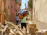 A young man in the village of Amizmiz is retrieving blankets from his home amid the rubble. (