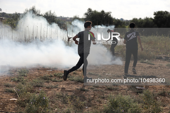 Palestinian protesters flee from tear gas during clashes with Israeli forces in a demonstration along the border between the Gaza Strip and...