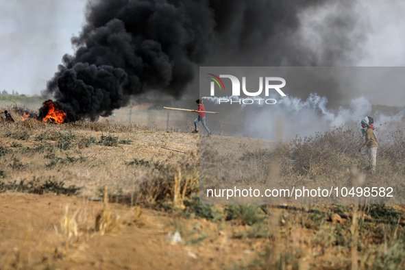 A Palestinian protester holds a tear gas canister fired by Israeli forces during a demonstration along the border between the Gaza Strip and...