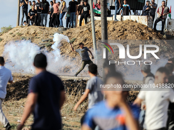 A Palestinian protester throws back a tear gas fired by Israeli security forces along the border fence during clashes with Israeli forces in...