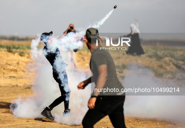 A Palestinian protester throws back a tear gas fired by Israeli security forces along the border fence during clashes with Israeli forces in...