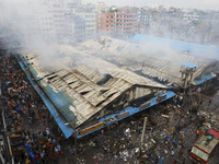 
Firefighters and volunteers are seen at the Mohammadpur Krishi Market, while smoke rises after a massive fire broke out, in Dhaka, Banglad...