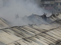 
Firefighters and volunteers are seen at the Mohammadpur Krishi Market, while smoke rises after a massive fire broke out, in Dhaka, Banglad...