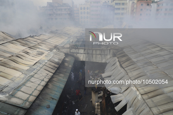 
Firefighters and volunteers are seen at the Mohammadpur Krishi Market, while smoke rises after a massive fire broke out, in Dhaka, Banglad...