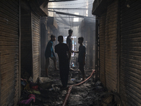 Shopkeepers look for the goods that survived from the massive fire at Mohammadpur Krishi Market in Dhaka on September 14, 2023. A massive bl...