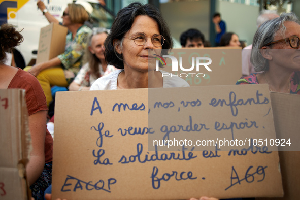 A woman holds a crdaboard reading 'For my, yours, ours children, I want to keep hope. Solidarity is our strenght'. A woman holds a cardboard...