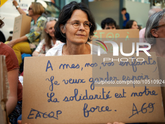 A woman holds a crdaboard reading 'For my, yours, ours children, I want to keep hope. Solidarity is our strenght'. A woman holds a cardboard...