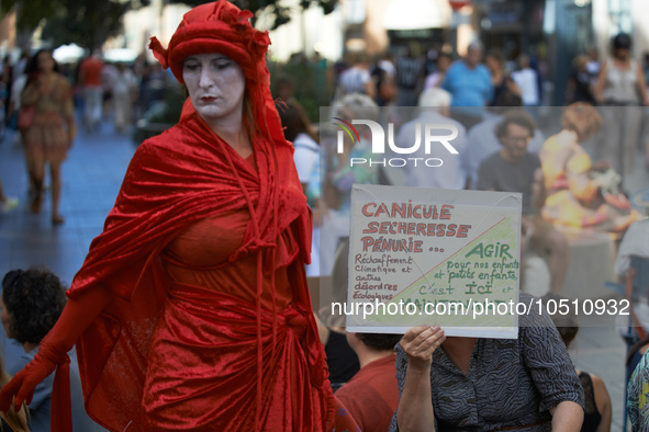 A Red Rebels walks in front of a placard reading 'Heatwave, floodings, Shortges... Act now for our children , it's now and here'. r Extincti...