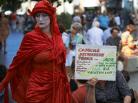 A Red Rebels walks in front of a placard reading 'Heatwave, floodings, Shortges... Act now for our children , it's now and here'. r Extincti...