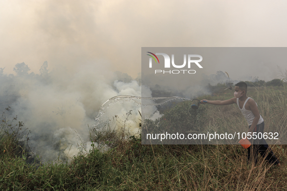 A small child in Soak Batok Village, North Indralaya District, Ogan Ilir Regency, South Sumatra is extinguishing forest and land fires on Mo...