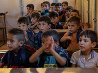 Photos taken on September 30, 2023, show Syrian students attending the first day of the new school year at a makeshift school inside a camp...