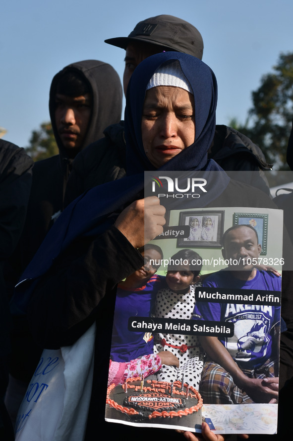 A mother is crying as she carries photos of the victims from the Kanjuruhan tragedy during a prayer to commemorate its first anniversary. Th...