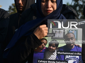 A mother is crying as she carries photos of the victims from the Kanjuruhan tragedy during a prayer to commemorate its first anniversary. Th...