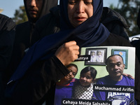 A mother is crying as she carries photos of the victims from the Kanjuruhan tragedy during a prayer to commemorate its first anniversary. Th...