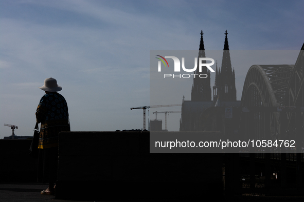 A woman is being seen on the other side of the Dom Cathedral in Cologne, Germany, on October 2, 2023, as the warm weather is bringing unusua...