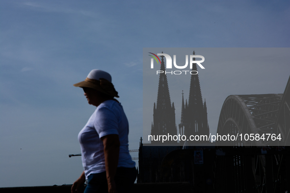 a woman is seen on the other side of dom cathedral in cologne, Germany on Oct. 2. 2023 as warm weather bring unusually hot october temeratur...