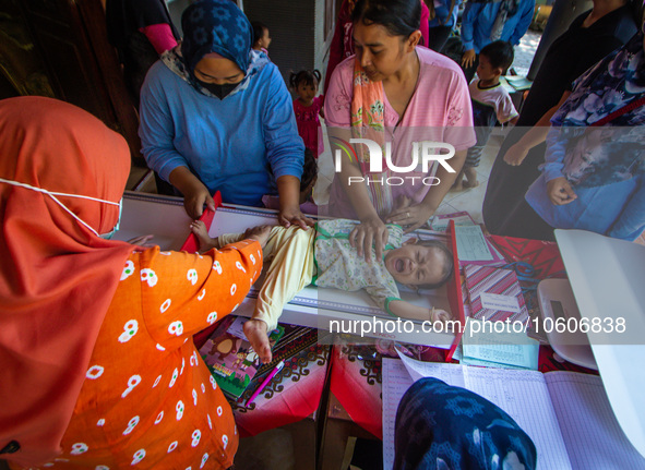 A baby is measured before receiving a Vitamin A capsule during a child stunting prevention programme at an integrated services post (POSYAND...